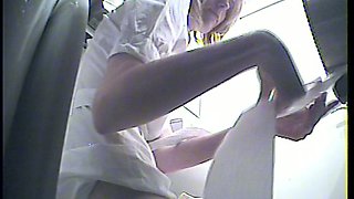 Blonde lady in white blouse and pants urinating in the toilet room